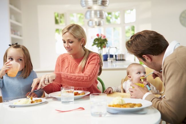 Family With Young Baby Eating Meal At Home