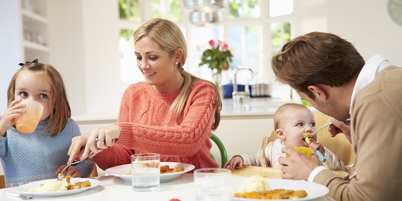 Family With Young Baby Eating Meal At Home