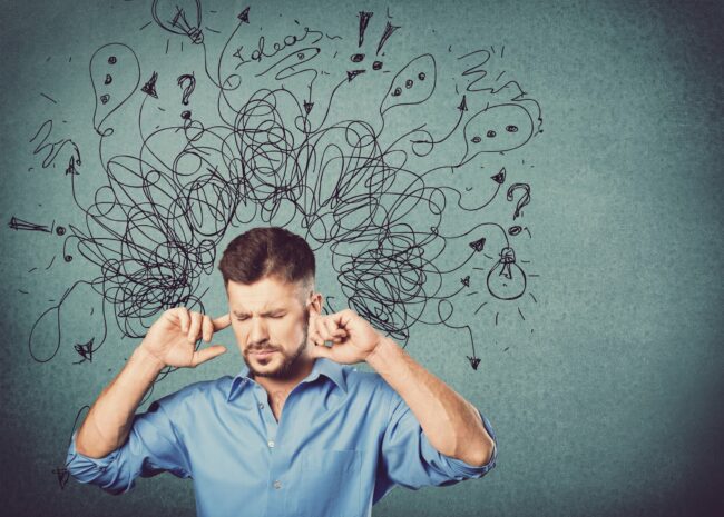 Ein Mann in einem blauen Hemd hält sich die Ohren zu, während verworrene Gedanken und Symbole über seinem Kopf schweben.